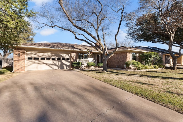 view of front of home with concrete driveway, brick siding, an attached garage, and a front yard