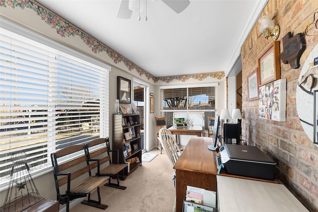 office area with a ceiling fan, light colored carpet, and brick wall