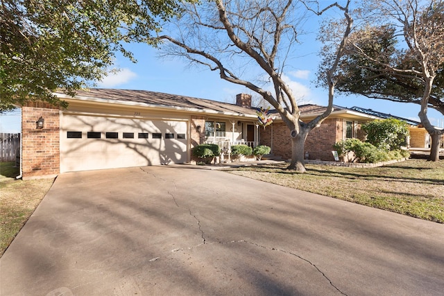 ranch-style home with driveway, an attached garage, a chimney, and brick siding