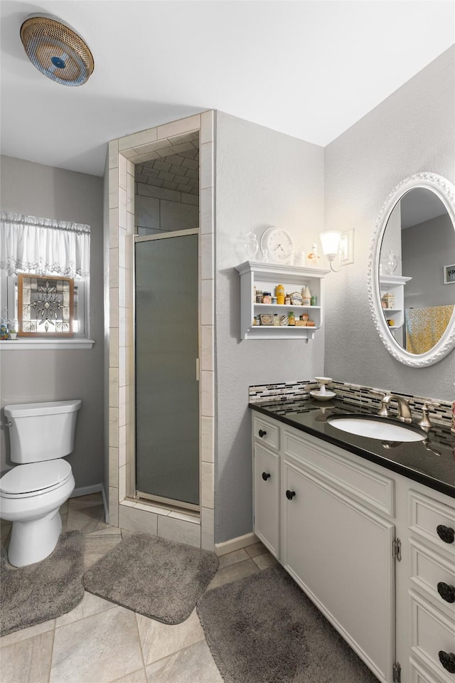 bathroom featuring a stall shower, baseboards, vanity, and toilet