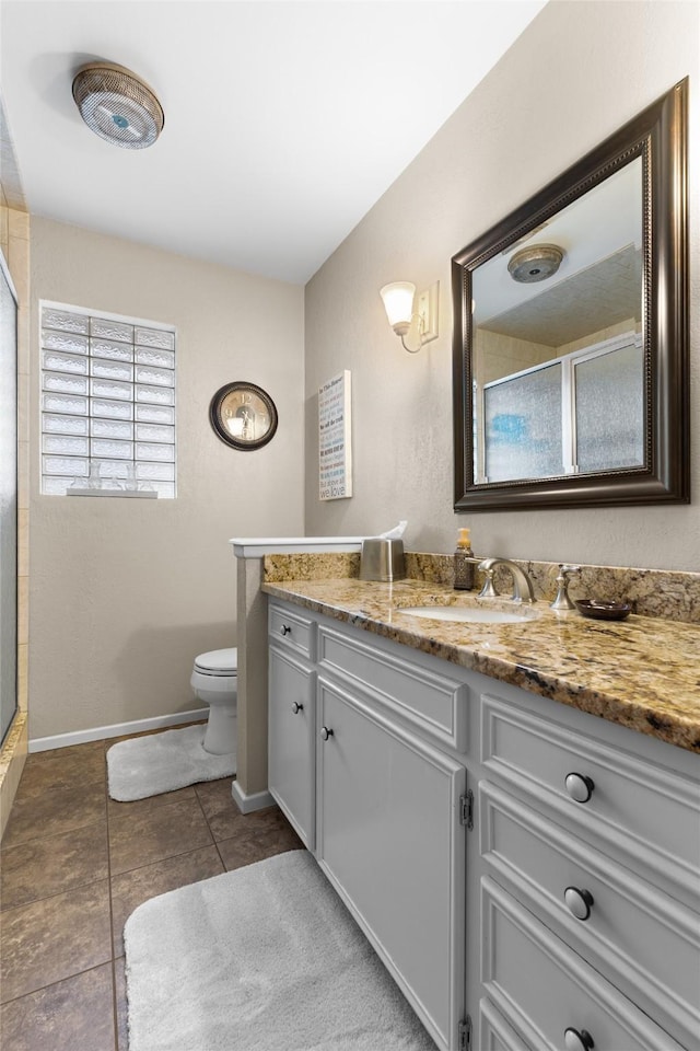 bathroom with baseboards, toilet, tile patterned floors, a shower with shower door, and vanity