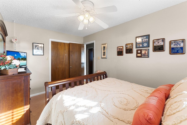 carpeted bedroom with a textured ceiling, a closet, a ceiling fan, and baseboards