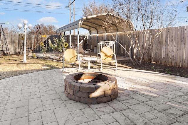 view of patio / terrace with a fenced backyard, a fire pit, and a detached carport