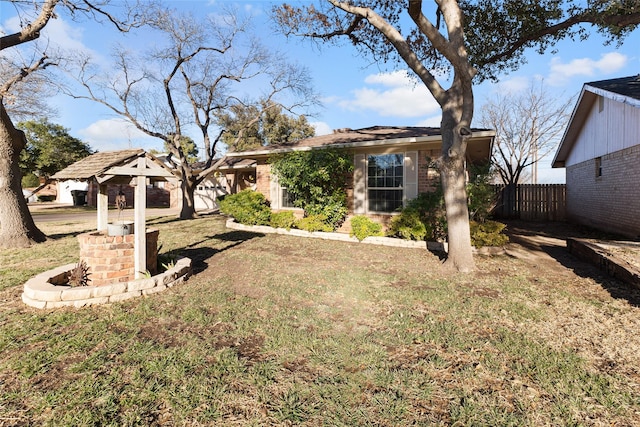 view of front facade with brick siding, a front lawn, and fence