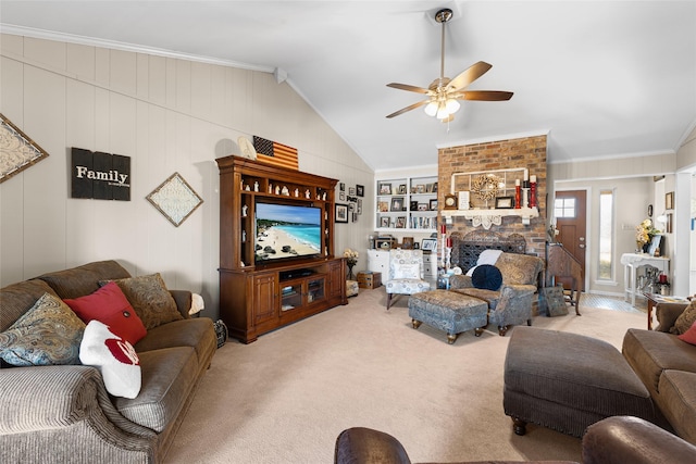 carpeted living room featuring ceiling fan, built in shelves, a fireplace, vaulted ceiling, and ornamental molding