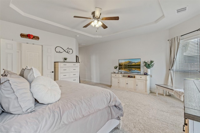 bedroom featuring visible vents, light carpet, baseboards, and a tray ceiling