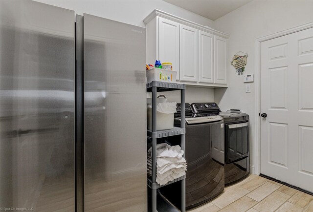 laundry area with washing machine and clothes dryer, cabinet space, and light wood finished floors