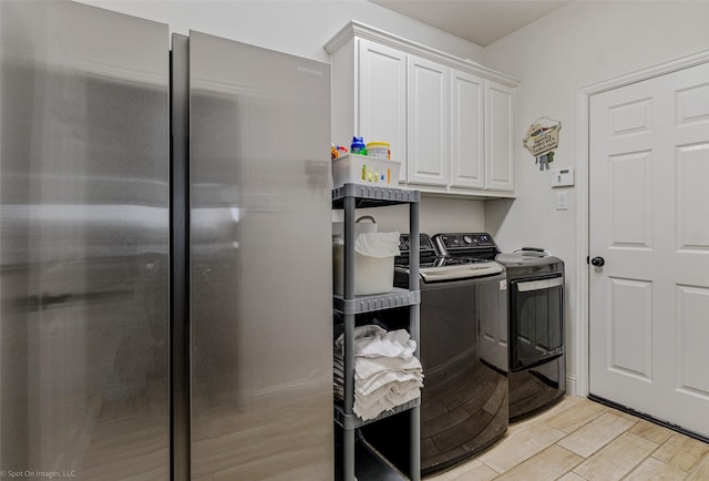 laundry area featuring wood finish floors, independent washer and dryer, and cabinet space