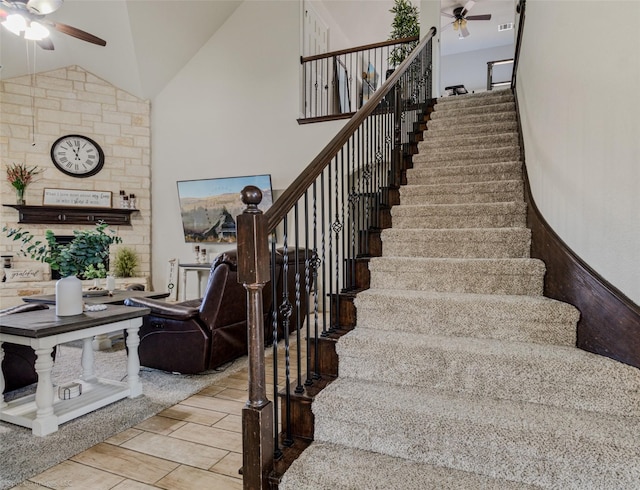 stairs featuring a ceiling fan, wood finish floors, and high vaulted ceiling