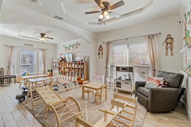 living room with arched walkways, a raised ceiling, visible vents, and wood finish floors