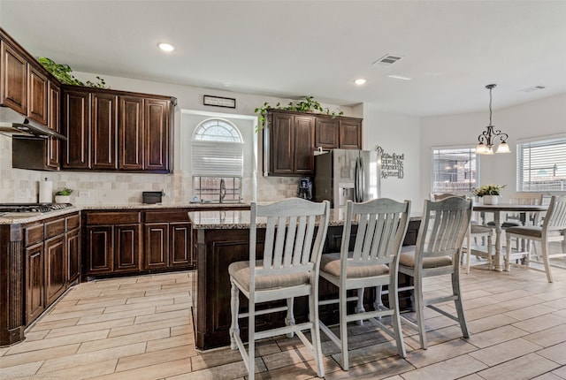 kitchen featuring wood tiled floor, tasteful backsplash, a kitchen breakfast bar, and stainless steel appliances