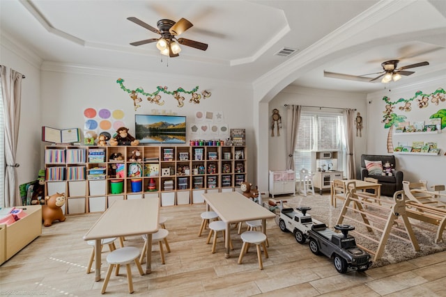 rec room featuring ornamental molding, arched walkways, a raised ceiling, and visible vents