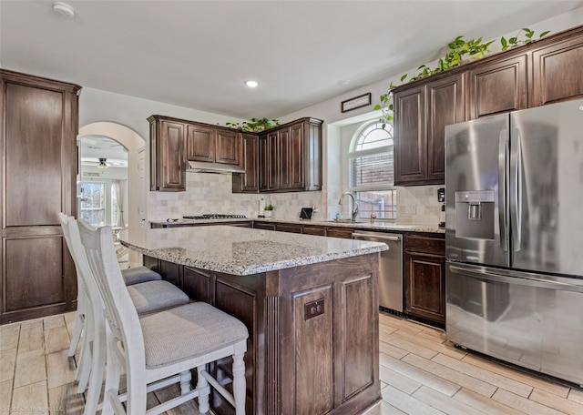 kitchen with dark brown cabinets, appliances with stainless steel finishes, tasteful backsplash, and a sink