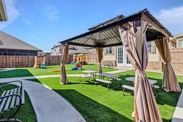 view of yard featuring a fenced backyard, a gazebo, a playground, and french doors