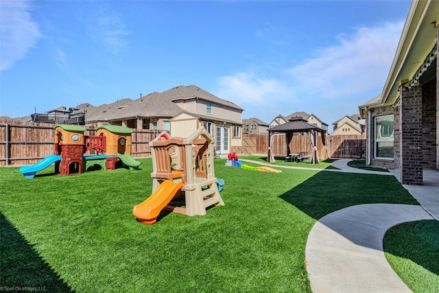 view of playground featuring a gazebo, a yard, a fenced backyard, and a residential view