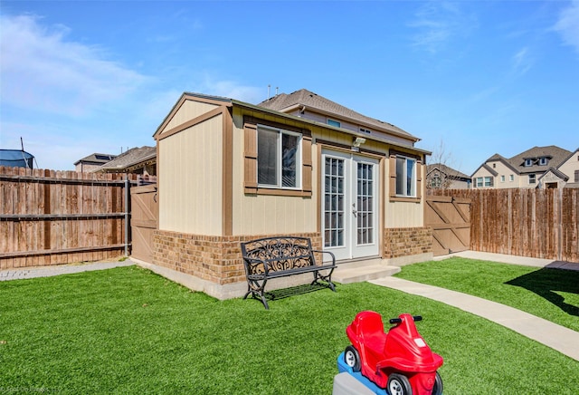 back of property featuring a lawn, a fenced backyard, french doors, and brick siding