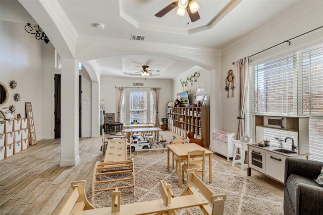 6025 Pine River Ln, Fort Worth, TX 76179 - living area with a ceiling fan, a tray ceiling, arched walkways, light wood-type flooring, and ornamental molding