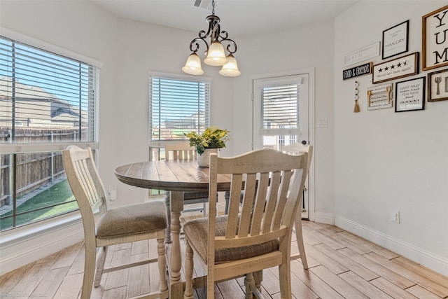 dining area featuring wood finish floors, baseboards, and a notable chandelier
