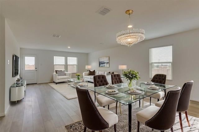 dining room with wood finished floors, visible vents, and a notable chandelier