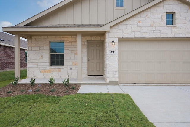 view of front of property featuring board and batten siding, stone siding, a front lawn, and an attached garage