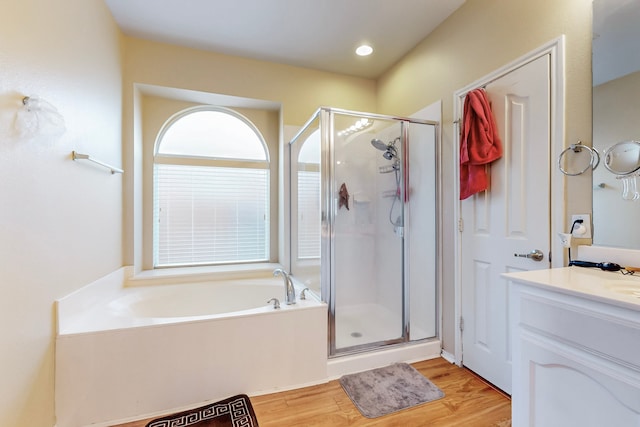 bathroom with a bath, a shower stall, vanity, and wood finished floors