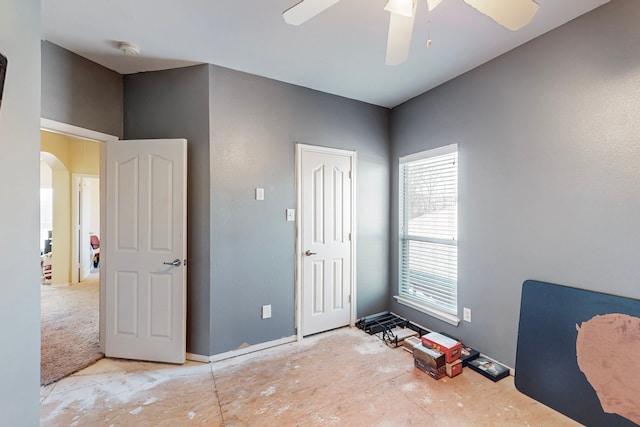 unfurnished bedroom featuring arched walkways and a ceiling fan