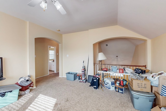 living room featuring a ceiling fan, carpet, vaulted ceiling, and arched walkways