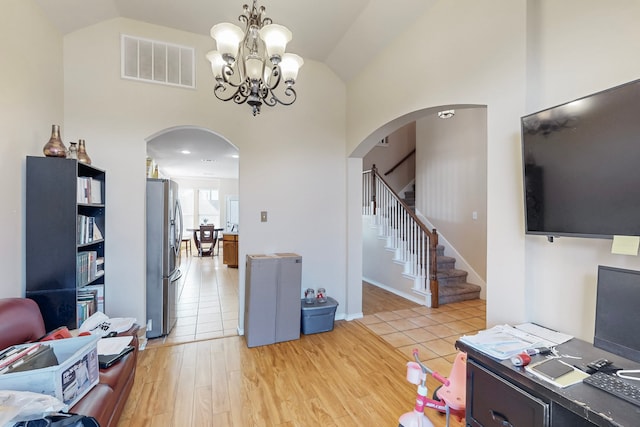 office area with arched walkways, high vaulted ceiling, visible vents, baseboards, and light wood-type flooring