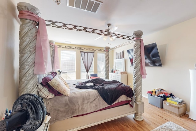 bedroom with wood finished floors, visible vents, and baseboards