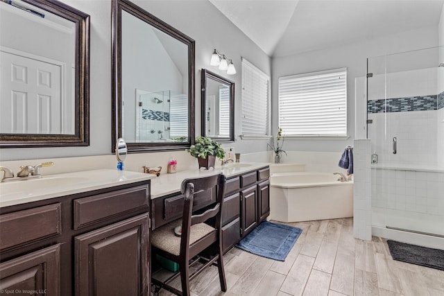 bathroom featuring lofted ceiling, a sink, a bath, double vanity, and a stall shower