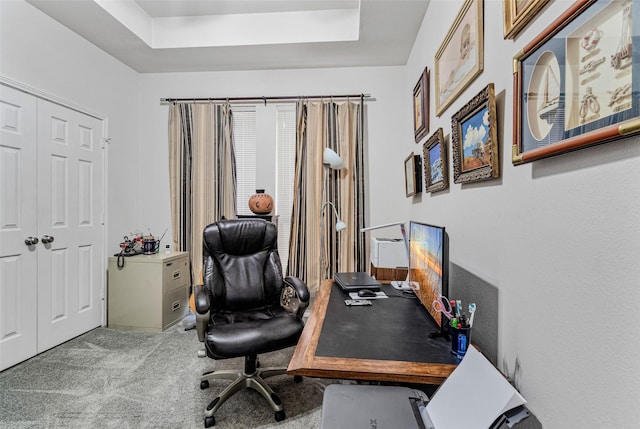 home office with carpet floors and a tray ceiling