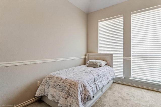 bedroom featuring lofted ceiling, baseboards, and carpet flooring