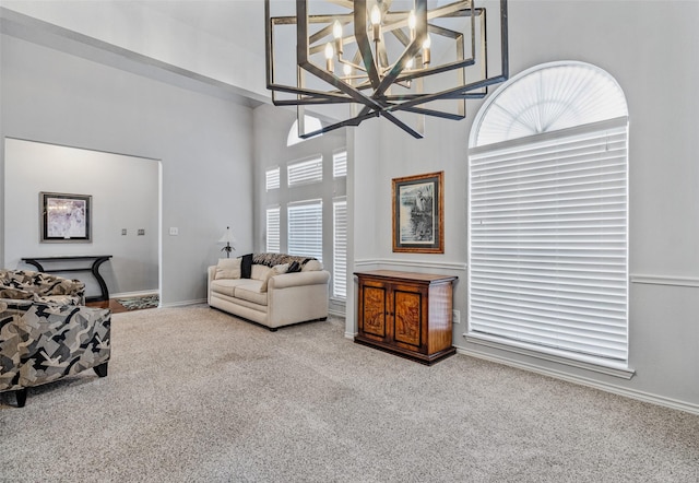 sitting room featuring carpet floors, an inviting chandelier, a high ceiling, and baseboards