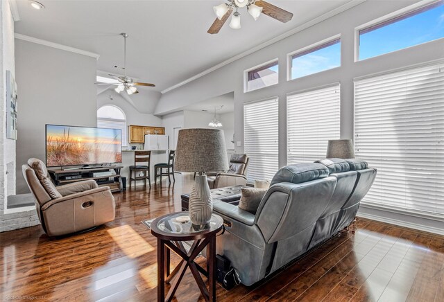 living area with ornamental molding, dark wood-type flooring, ceiling fan, and a high ceiling