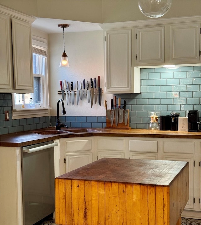 kitchen with tasteful backsplash, butcher block counters, stainless steel dishwasher, white cabinetry, and a sink