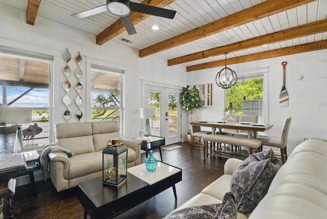 living room with ceiling fan with notable chandelier, wood finished floors, beam ceiling, and a healthy amount of sunlight