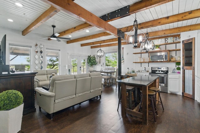 living room featuring beamed ceiling, dark wood finished floors, recessed lighting, and ceiling fan with notable chandelier