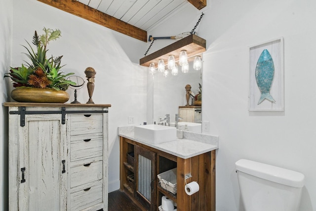 bathroom with toilet, beamed ceiling, wood finished floors, wooden ceiling, and vanity