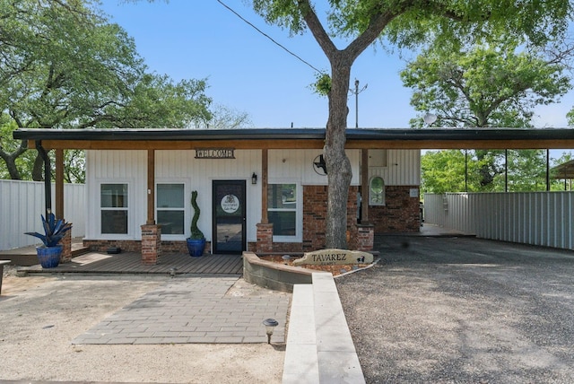 bungalow-style house featuring fence, brick siding, and a carport