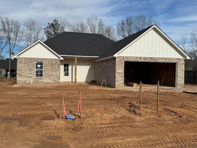 view of front facade with a garage, brick siding, and a shingled roof