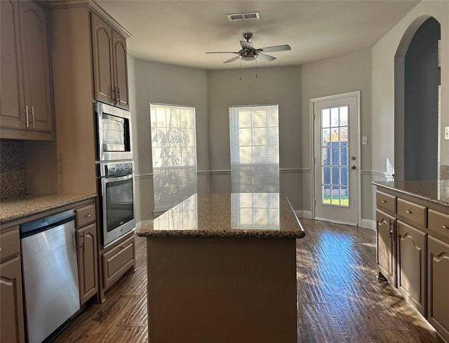 kitchen with arched walkways, stainless steel appliances, a kitchen island, visible vents, and dark wood-style floors