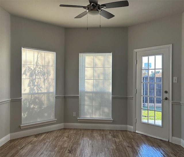 doorway with a ceiling fan, baseboards, and wood finished floors