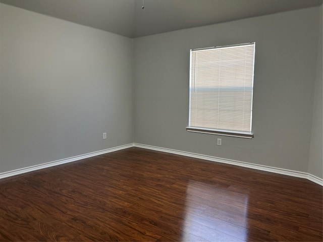 spare room with dark wood finished floors and baseboards