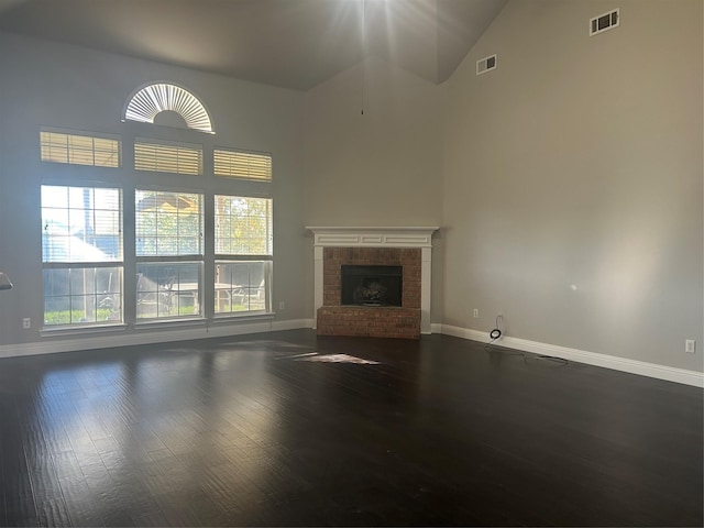 unfurnished living room featuring dark wood-style floors, a brick fireplace, and visible vents