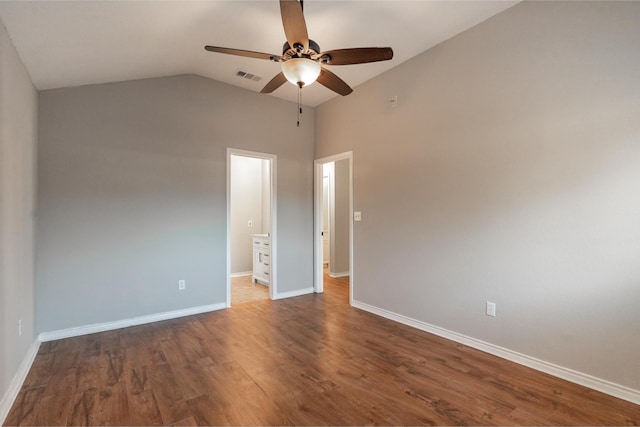 empty room with baseboards, visible vents, ceiling fan, wood finished floors, and vaulted ceiling