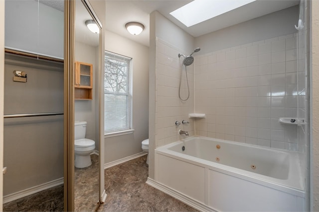 full bathroom with a skylight, a combined bath / shower with jetted tub, toilet, and baseboards