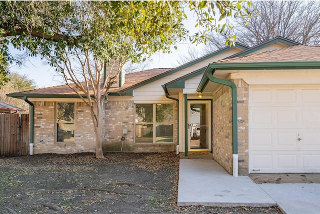 single story home with an attached garage, fence, and brick siding