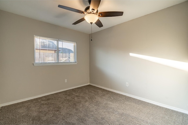 unfurnished room featuring ceiling fan, dark carpet, and baseboards