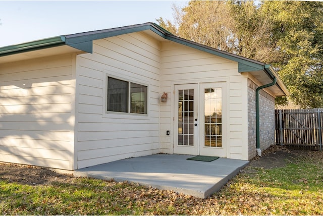 back of house featuring french doors, brick siding, a patio area, and fence