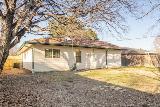 rear view of property with fence and a lawn